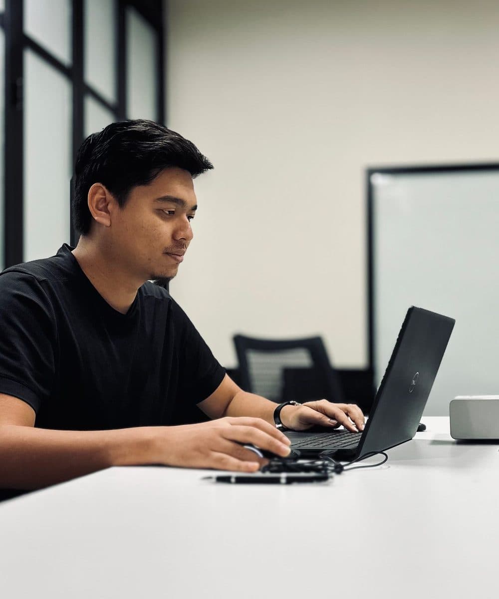 A young man working on a laptop in a modern meeting room